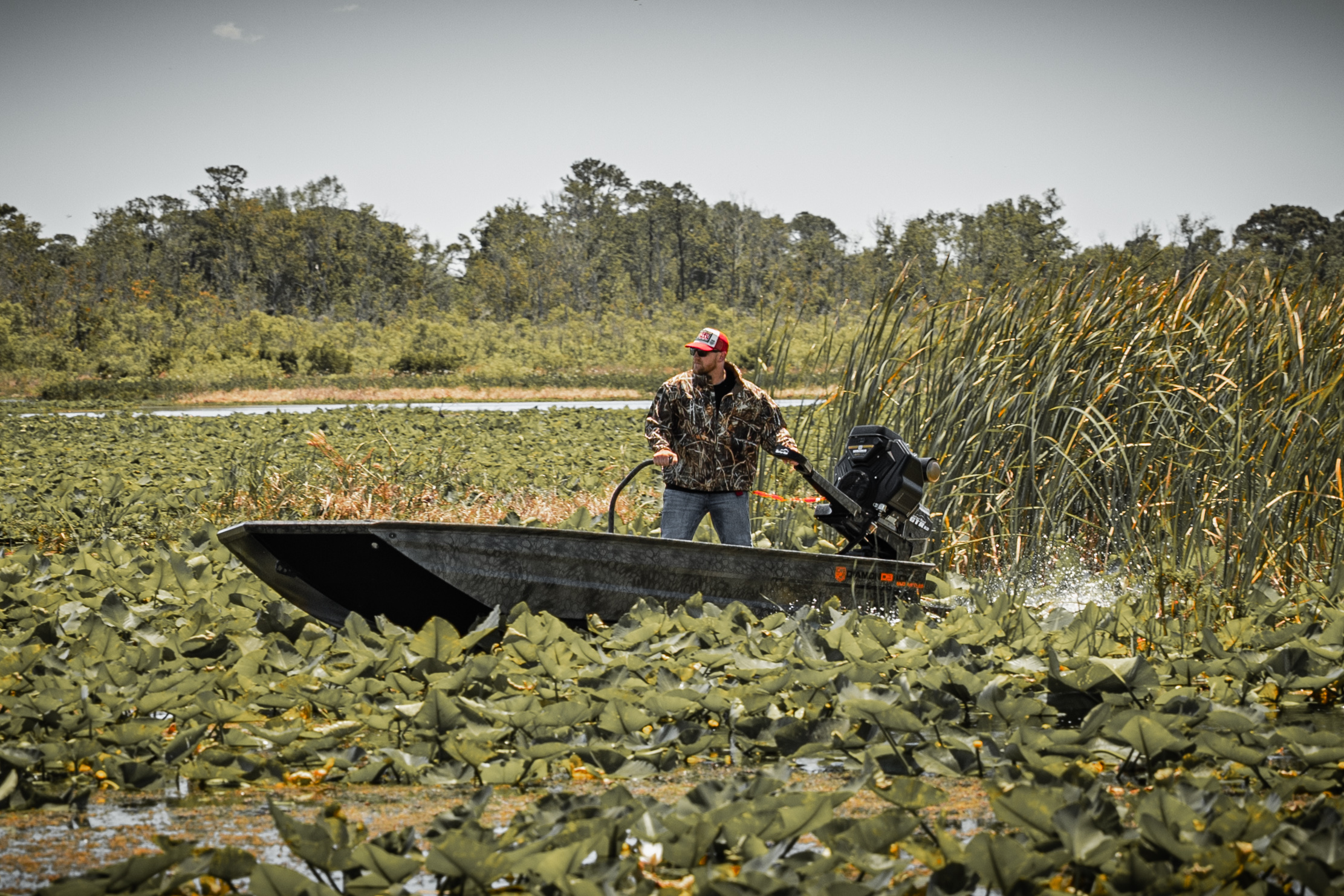 Diamondback mud boat navigating through marsh lily pads during hunting season